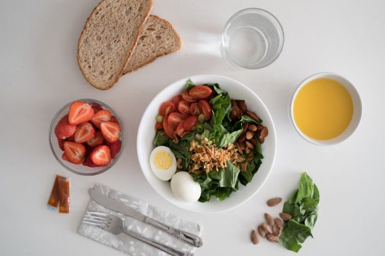 Top view of a nutritious breakfast with salad, eggs, bread, and juice, perfect for a healthy start.