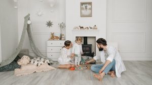 Warm family scene of parents playing with their daughter in a cozy white room.