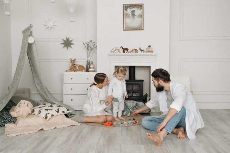 Warm family scene of parents playing with their daughter in a cozy white room.